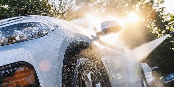 A white vehicle receiving a careful exterior rinse